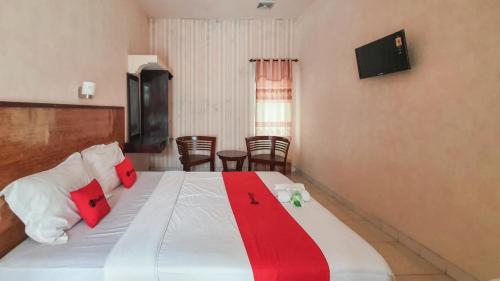 a bedroom with a large bed with red and white pillows at RedDoorz At Pujon Malang in Batu