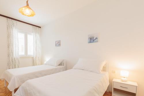 dwa łóżka w białej sypialni z oknem w obiekcie Buena Vida Apartman w mieście Zadar
