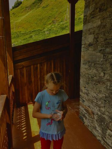 a little girl standing in a room looking at her cell phone at Qaldea Resort in Ushguli