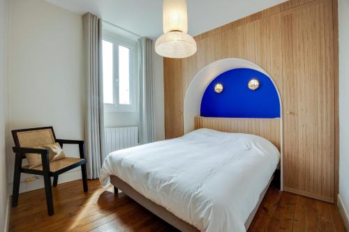 um quarto com uma cama com uma cabeceira azul e uma cadeira em Villa Les Hirondelles - Appartement avec Jardin Front de mer em Saint-Aubin-sur-Mer