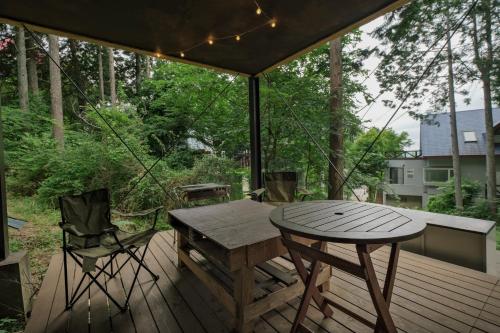 einen Holztisch und Stühle auf einer Holzterrasse in der Unterkunft 南箱根ツリーハウス in Kannami