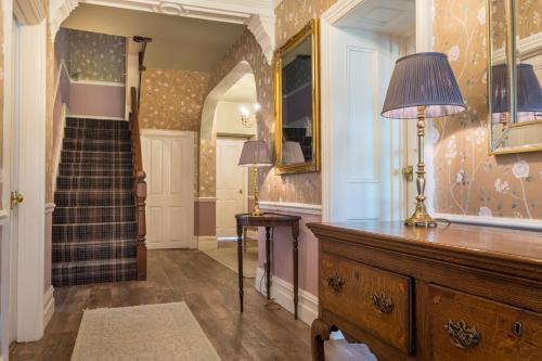 a hallway with a dresser with a lamp and a staircase at Swinside Lodge in Keswick