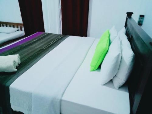 a bed with green and white pillows on it at Bangalawa Resort in Habarana
