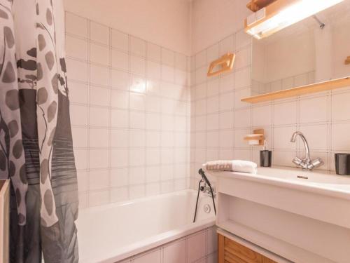 ein weißes Badezimmer mit einer Badewanne und einem Waschbecken in der Unterkunft Appartement Saint-Chaffrey , 1 pièce, 4 personnes - FR-1-330E-44 in Saint-Chaffrey
