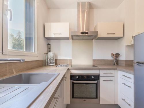 une cuisine blanche avec un évier et une cuisinière dans l'établissement Appartement 3 pièces, 6 couchages - Chantemerle, Serre-Chevalier, balcon, parking, casier à ski - FR-1-330E-9, à Saint-Chaffrey