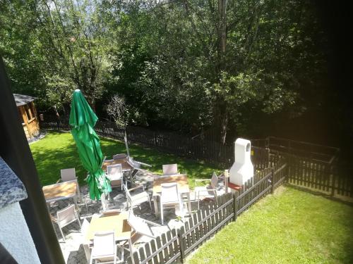 a group of tables and chairs with a green umbrella at Tischlmühle Appartements & mehr in Gröbming