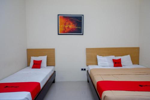 two beds in a room with red pillows at RedDoorz Syariah At Namira Hotel in Yogyakarta