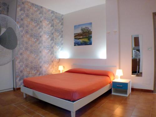 a bedroom with a bed with orange sheets and a mirror at Casa Vacanze Donn'Anna in Porto Cesareo