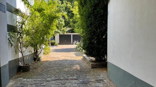 a cobblestone alley way with a building and trees at OASE im grünen Hinterhof, EG, Ruhe, Terrasse, Carport, free PayTV, Kaffee&Tee, Fahrräder in Duisburg