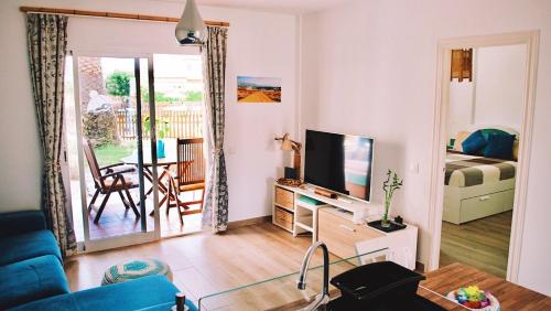 a living room with a blue couch and a television at Bamboo House in Corralejo