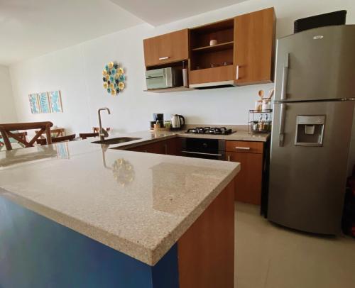 eine Küche mit einem Kühlschrank aus Edelstahl und Holzschränken in der Unterkunft Paraíso frente al Mar Caribe en Cartagena. in Cartagena de Indias