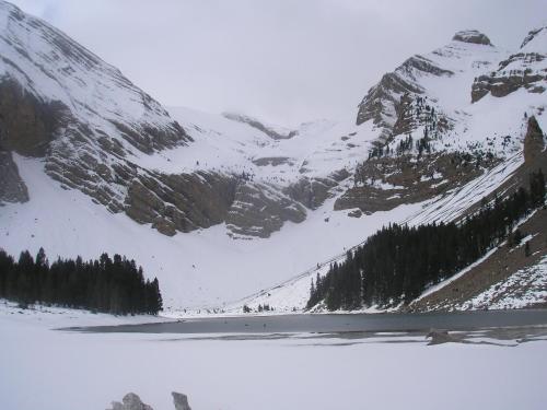 a snow covered mountain with a lake in front of it at Apartamentos Casa Borja in Salinas de Bielsa