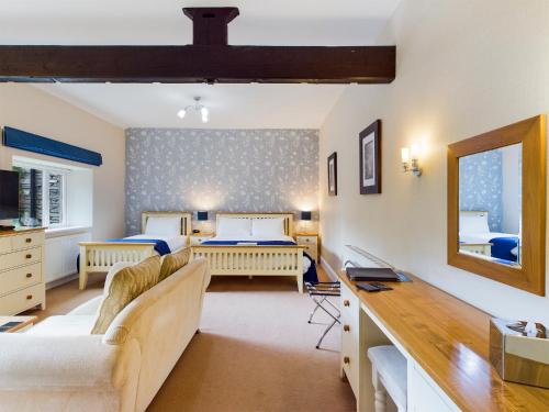 a bedroom with two beds and a desk with a mirror at Crow How Country Guest House in Ambleside