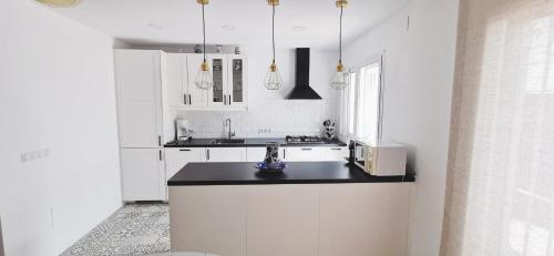 uma cozinha com armários brancos e um balcão preto em Casa Adosada Bel Andalus em Estepona