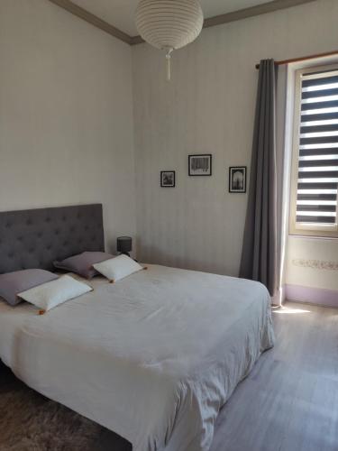 a bedroom with a large white bed with a window at Gîte Chanay 80 m2 Tournus 2 chambres in Tournus