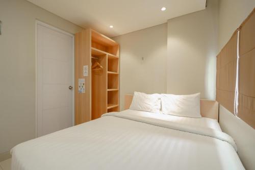 a bedroom with a white bed and a closet at Green Apple Residence near Sarinah Mitra RedDoorz in Jakarta