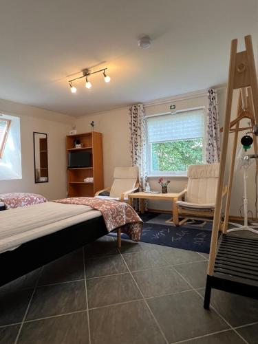 a bedroom with a bed and chairs and a window at Gästhus La Casa in Sölvesborg