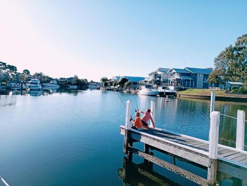 two people sitting on a dock on a body of water at Captains Cove Ground Floor Luxury Apartments - Free Netflix in Paynesville
