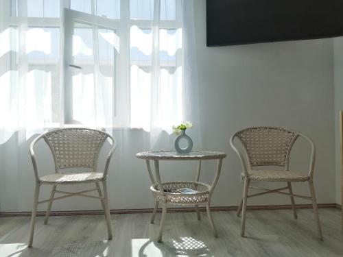 two chairs and a table with a vase on top of it at PortStreet apartamenti in Liepāja