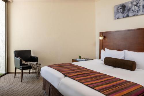 a hotel room with a bed and a chair at Leonardo Inn Hotel Dead Sea in Ein Bokek