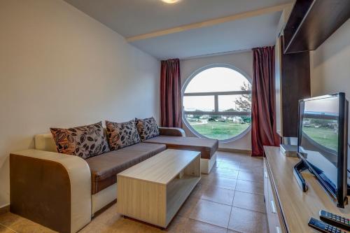 a living room with a couch and a tv at Saint George Hotel 1 in Balchik