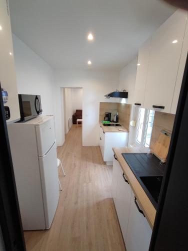 une cuisine avec des armoires blanches et un plancher en bois dans l'établissement Alsace N°3, au Mans