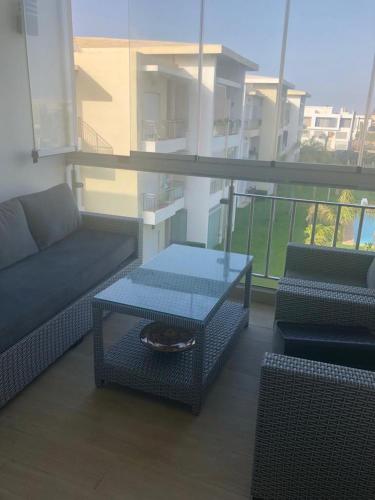 a living room with a couch and a table on a balcony at Bel appartement pied sur mer vue imprenable sur piscine et jardins in Sidi Rahal