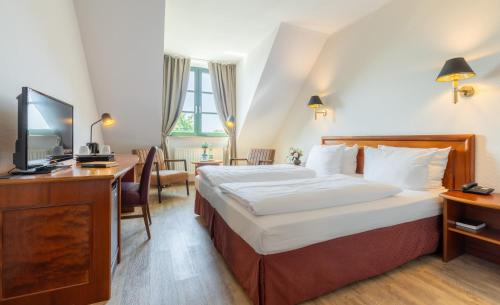 a hotel room with a large bed and a desk at Hotel Ohlenhoff in Norderstedt