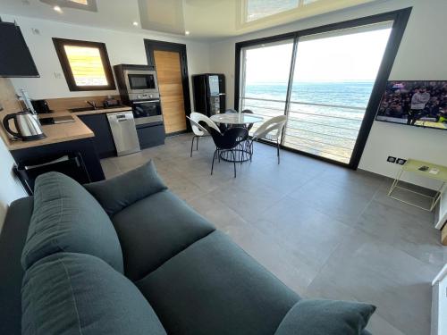 Il comprend un salon avec un canapé, une cuisine et une table. dans l'établissement maison de bord de mer cap corse, à Santa-Maria-di-Lota