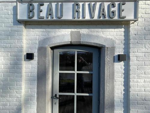 une porte menant à un bâtiment avec un panneau au-dessus de celui-ci dans l'établissement Gîte de charme bord de Meuse, à Namur