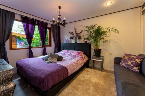 a bedroom with a purple bed and a couch at Chalet Heppie People in Doornspijk