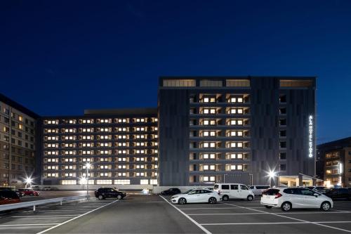 a large building with cars parked in a parking lot at ALA HOTEL KYOTO in Kyoto
