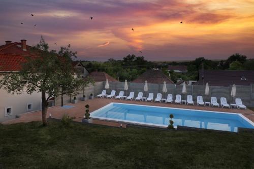 una piscina con sedie e un tramonto sullo sfondo di Trend Apartmanház -Vizslás a Vizslás