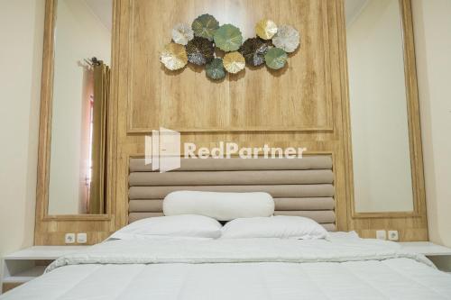 a white bed in a bedroom with a sign above it at Guest House B Fren Syariah Near JIH Yogyakarta Mitra RedDoorz in Seturan
