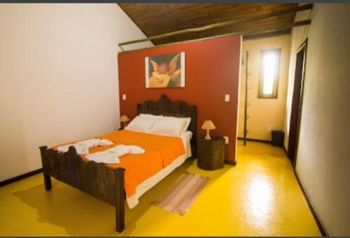 1 dormitorio con 1 cama grande de color naranja en una habitación en Pousada Jardim Cambuí Beach, en Itacimirim
