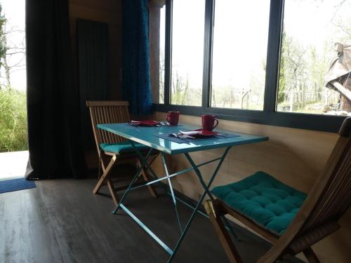 une table et des chaises dans une pièce avec une fenêtre dans l'établissement Chambre dans gîtes indépendant en Périgord Noir, à Segonzac