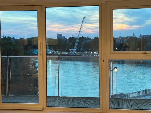 a room with three windows with a view of a river at Best Location Chelsea River View /Central London in London