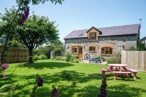 a stone house with a picnic table in a yard at Croft Farm & Celtic Cottages in Cardigan