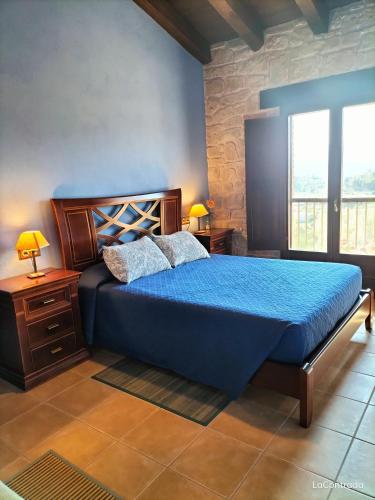 a bedroom with a blue bed and a window at La Contrada in Arens de Lledó