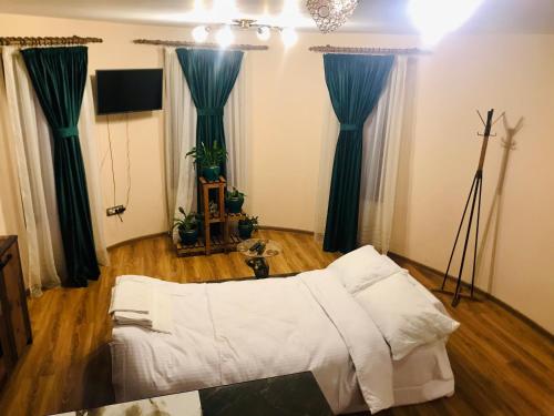 uma sala de estar com uma cama branca e cortinas azuis em Apartament La Vilă em Curtea de Argeş