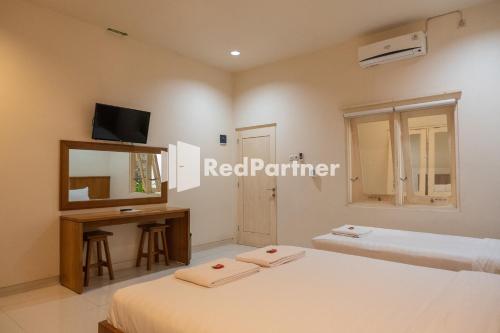 a bedroom with two beds and a desk and a mirror at Villa Dora Jogja Mitra RedDoorz near Malioboro Area in Sentool