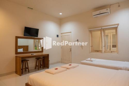 a bedroom with two beds and a desk and a mirror at Villa Dora Jogja near Malioboro Area Mitra RedDoorz in Sentool