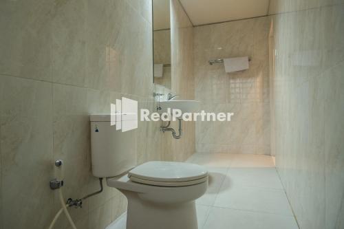 a white bathroom with a toilet and a sink at Villa Dora Jogja near Malioboro Area Mitra RedDoorz in Sentool