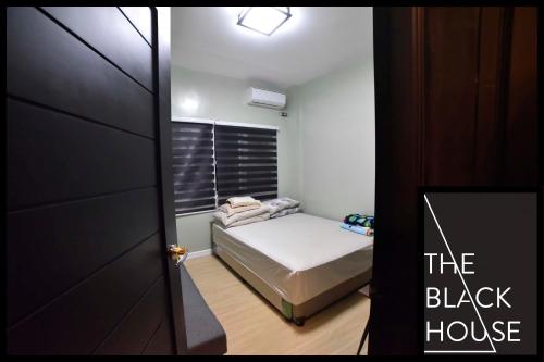 ein kleines Schlafzimmer mit einem Bett und ein schwarzes Haus in der Unterkunft The Black House in Dulong Bayan