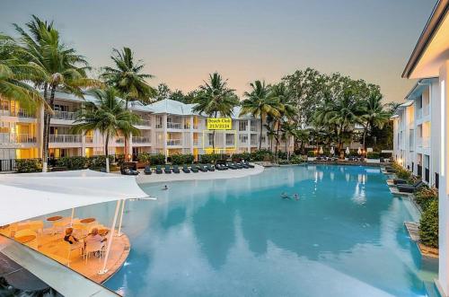 a pool at a resort with palm trees and buildings at Beach Club Port Douglas Luxury Apartments in Port Douglas
