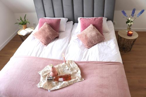 a pink and white bed with a bottle of wine on it at Apartamenty Pardałówka 50 in Zakopane