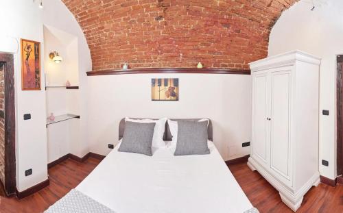 a bedroom with a white bed and a brick wall at Dom Unirii Apartment in Timişoara