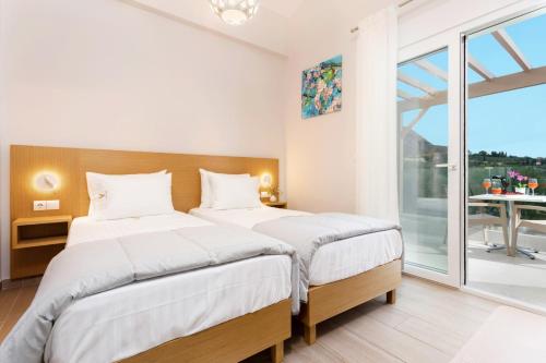 2 Betten in einem Schlafzimmer mit einem großen Fenster in der Unterkunft Villa Vilenia Horizon by Villa Plus in Katastárion