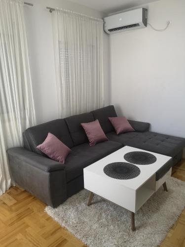 salon z czarną kanapą i białym stołem w obiekcie Jednosoban stan Zoja w mieście Podgorica