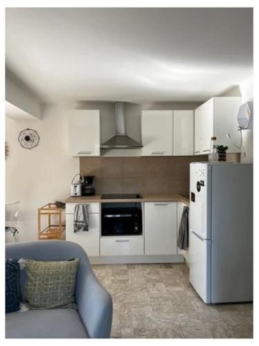 La cuisine est équipée de placards blancs et d'un réfrigérateur. dans l'établissement Appartement duplex plein sud sur le port de Bonifacio, à Bonifacio